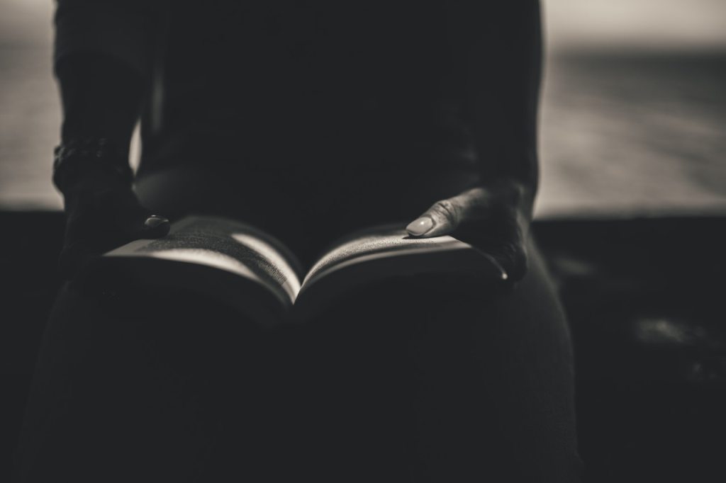 black and white image of women holding open book